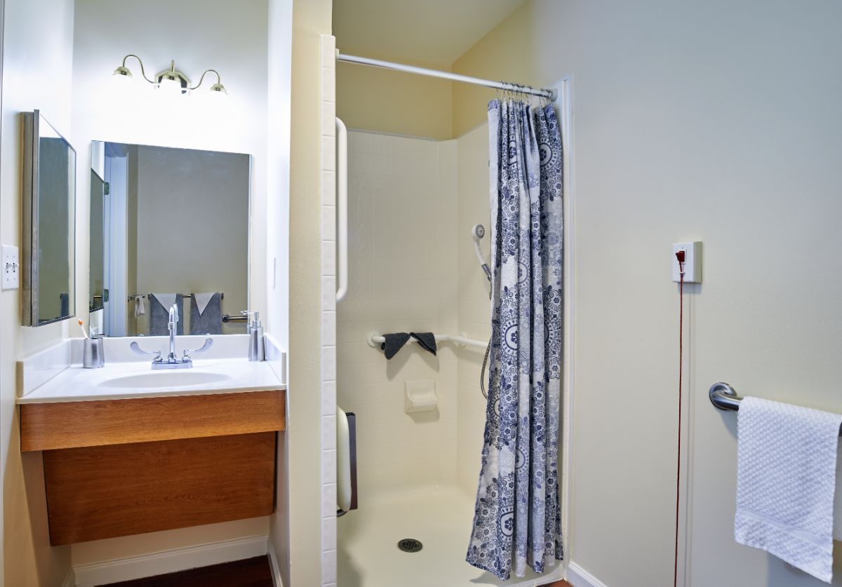A bathroom with a shower, patterned curtain, and a vanity sink with a mirror.