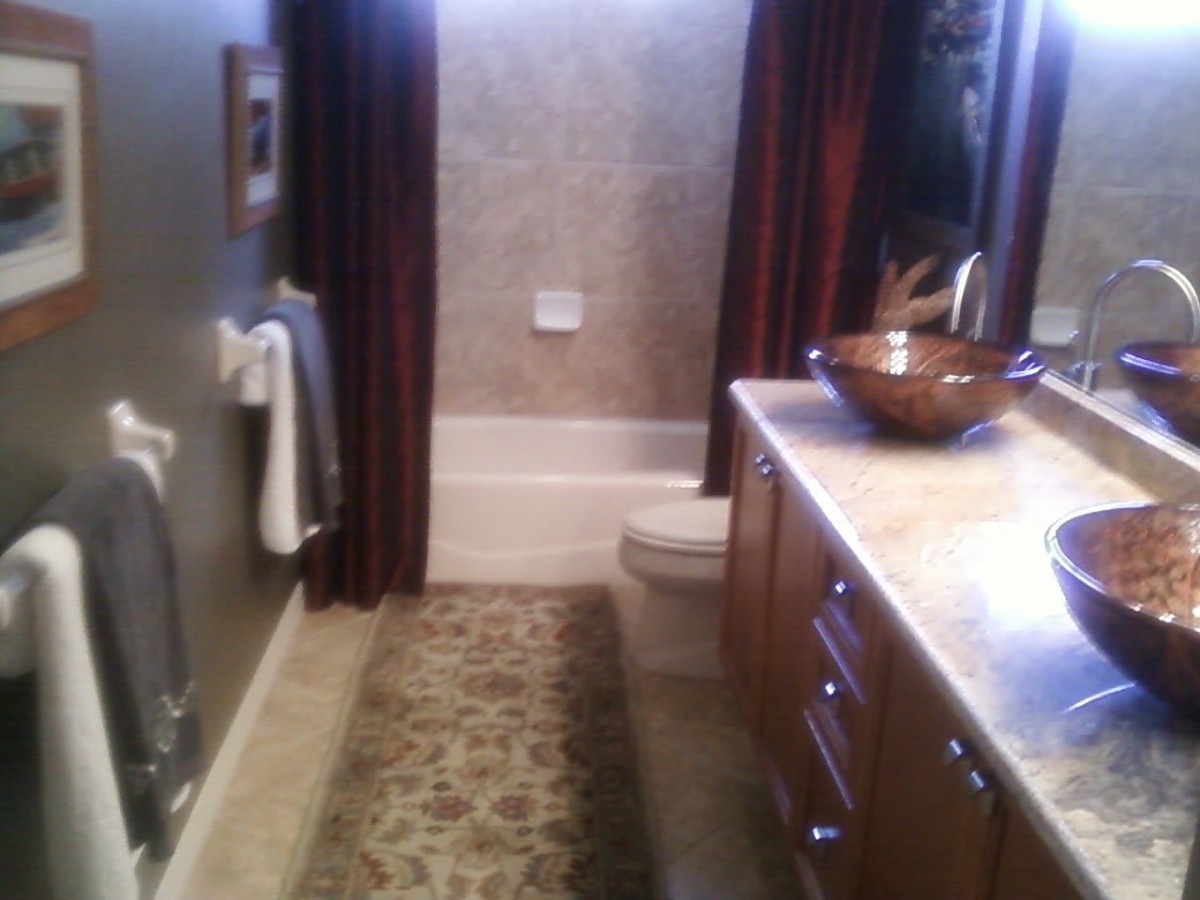 A modern bathroom with a vessel sink, dark curtains, and a patterned rug.