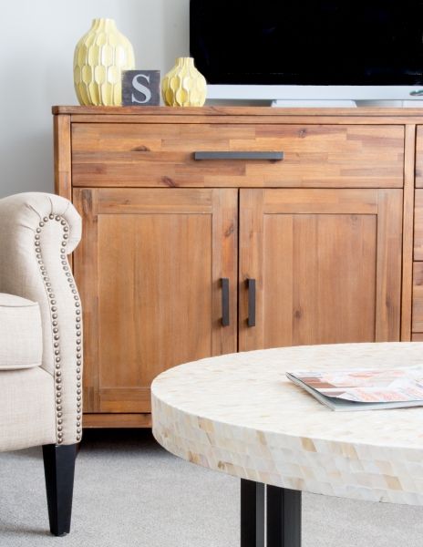 A cozy living room featuring a wooden cabinet, an upholstered armchair, and a round coffee table.