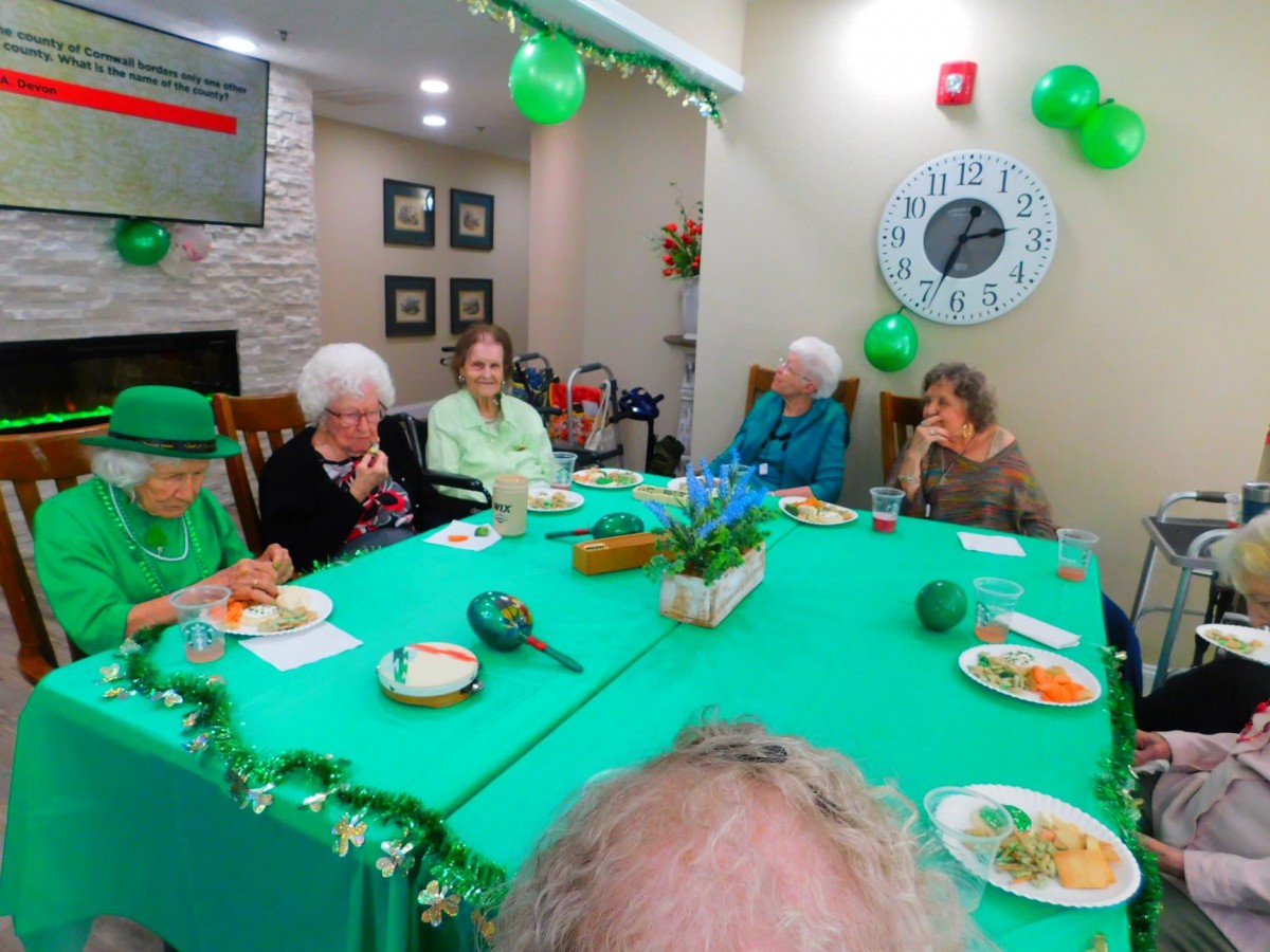 A group of elderly people enjoying a festive gathering with green decorations.