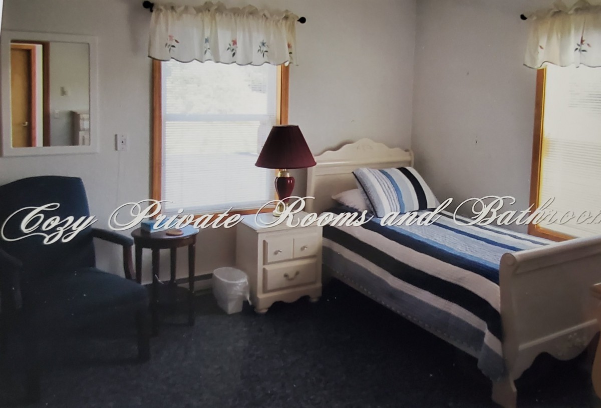 A cozy bedroom featuring a single bed with striped bedding, a nightstand with a lamp, and a window with a curtain.