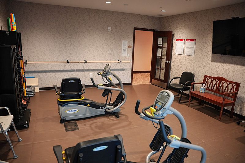 A small fitness room equipped with cardio machines including an elliptical trainer and a recumbent bike.