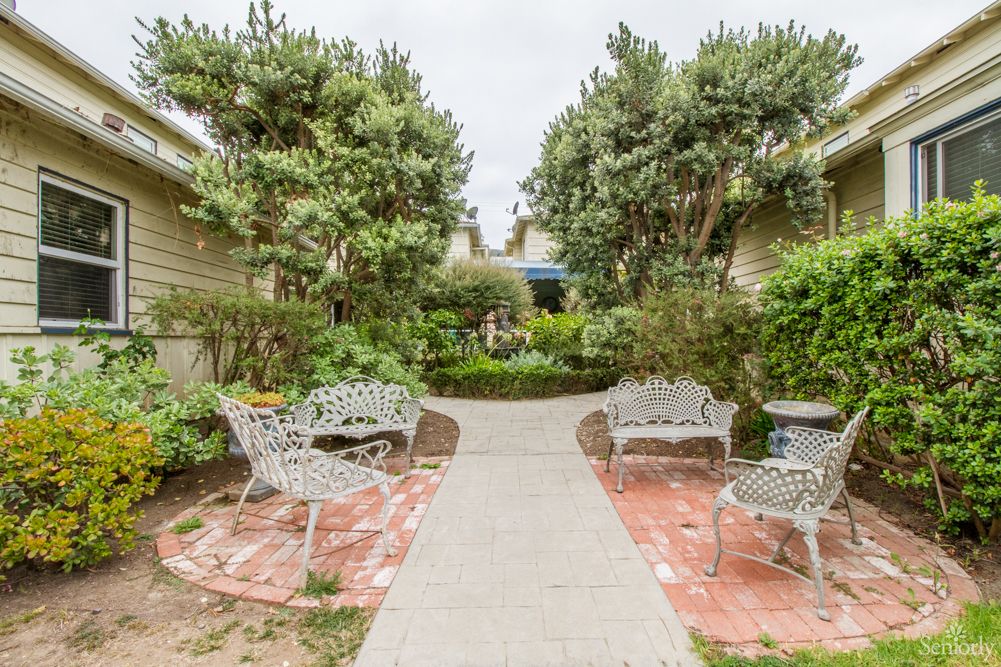 A serene garden pathway with benches and lush greenery.