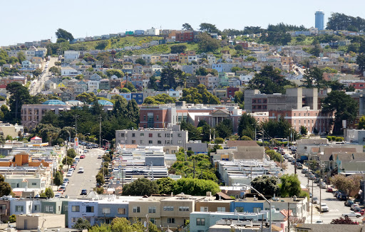 A view of a vibrant residential neighborhood with hills in the background.
