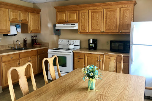 A cozy kitchen featuring wooden cabinets and a dining table adorned with flowers.
