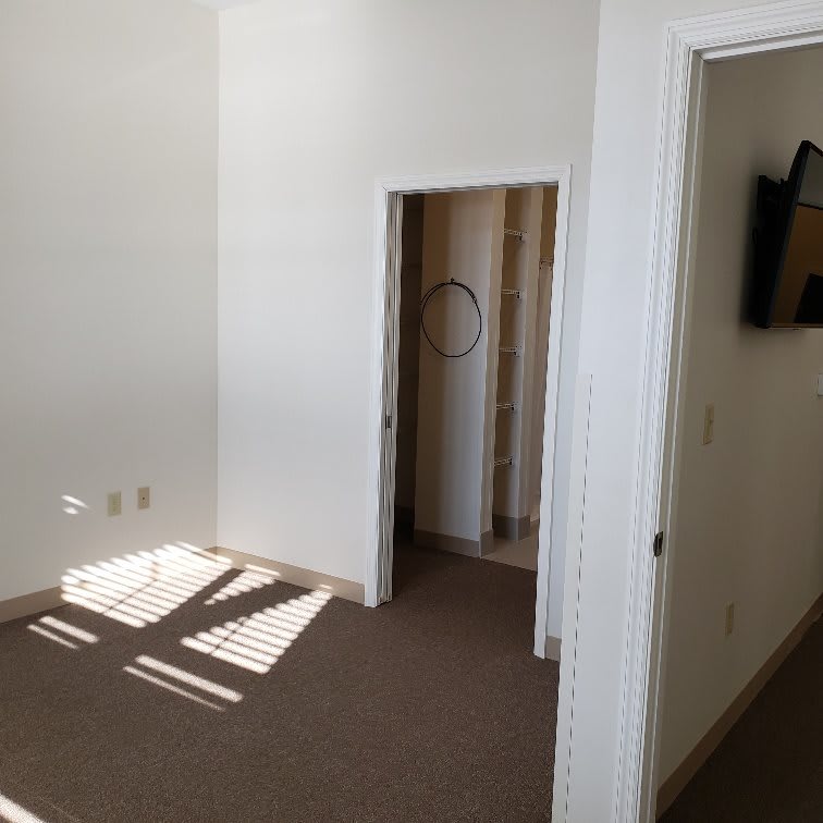 An empty room with a carpet and a doorway leading to another area.