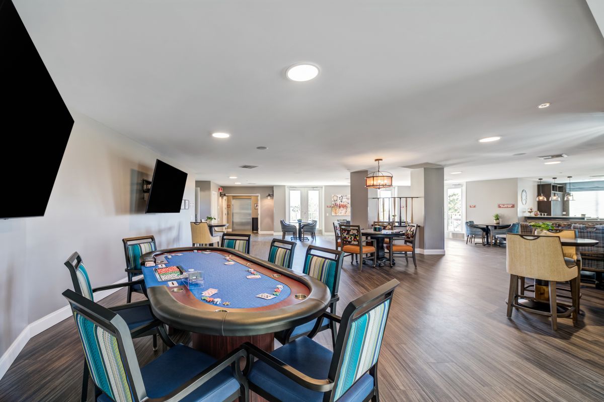 A spacious game room featuring a poker table, comfortable seating, and a television.