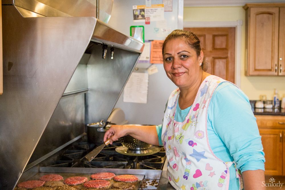 A woman cooking at a stove in a kitchen.