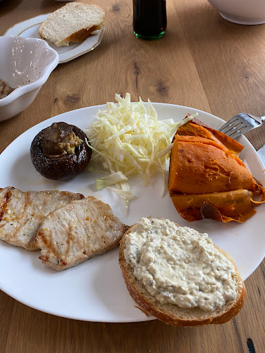 A colorful and healthy plate featuring grilled meat, sweet potato, cabbage salad, and other vegetables.