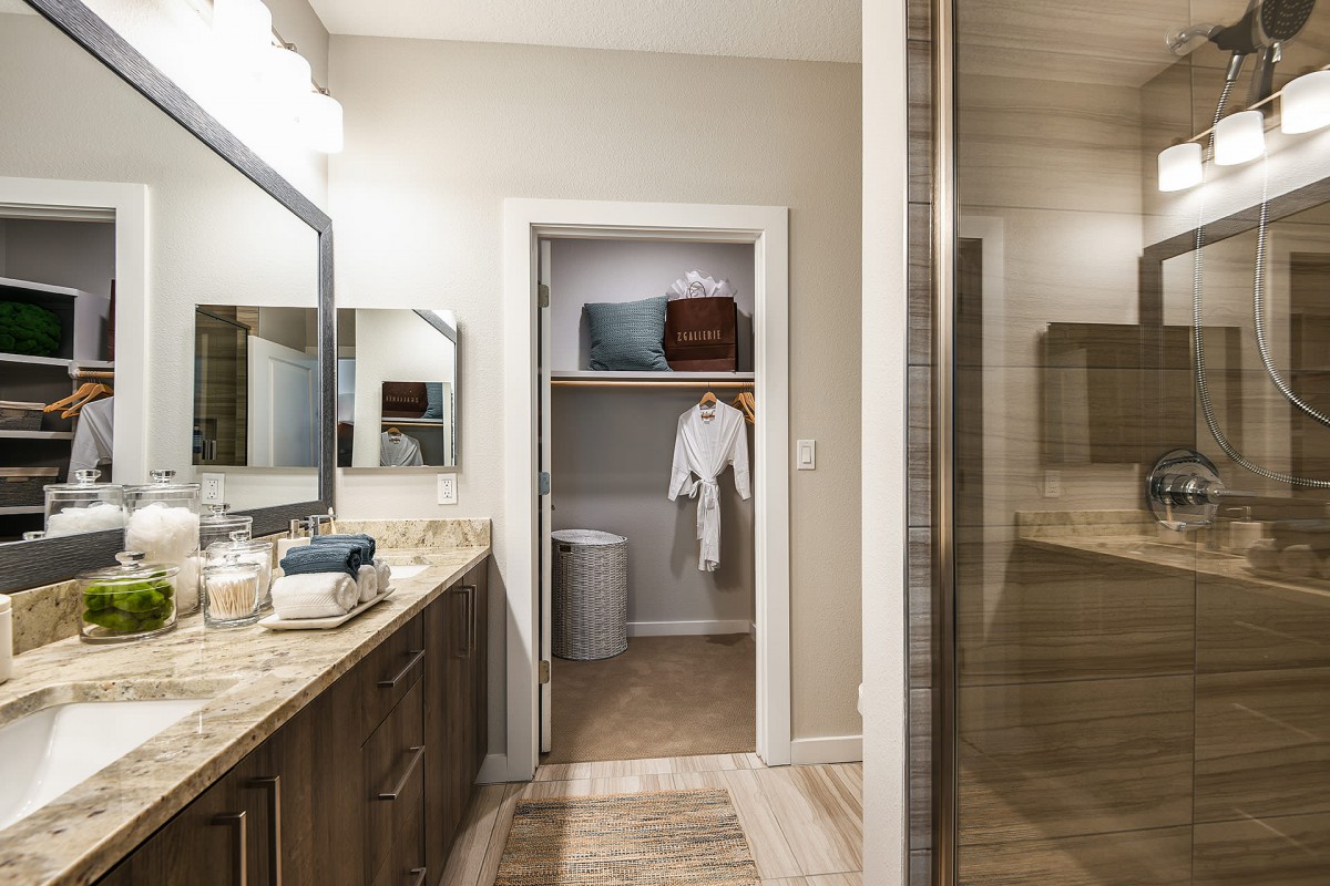 A modern bathroom with a view of the vanity and an open closet containing robes.