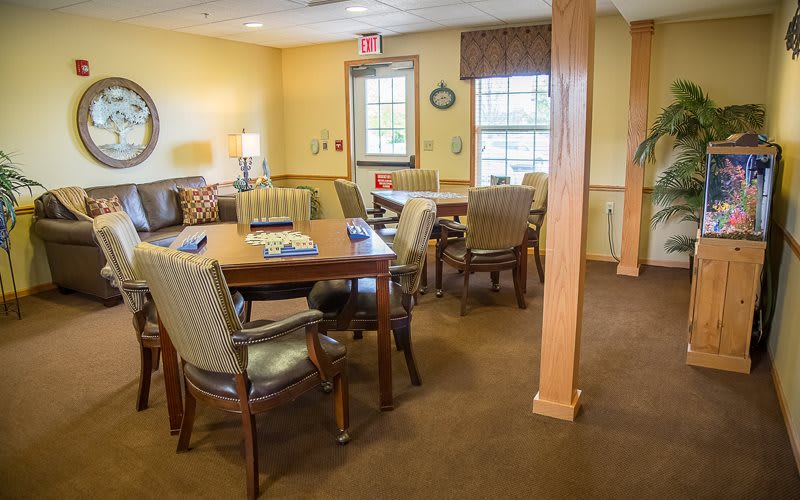 A cozy meeting room with tables and chairs, softly lit by lamps.
