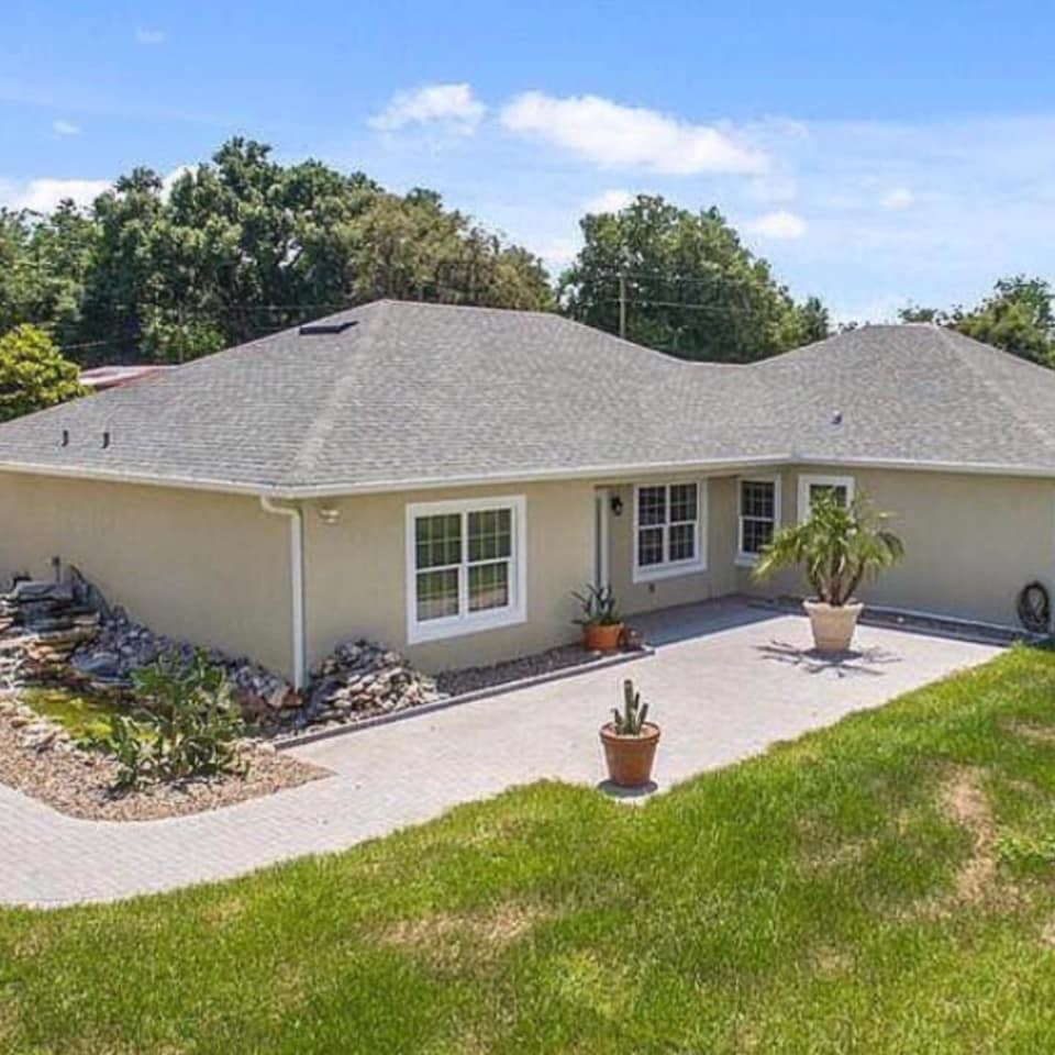 A single-story house with a patio and surrounding landscaping.