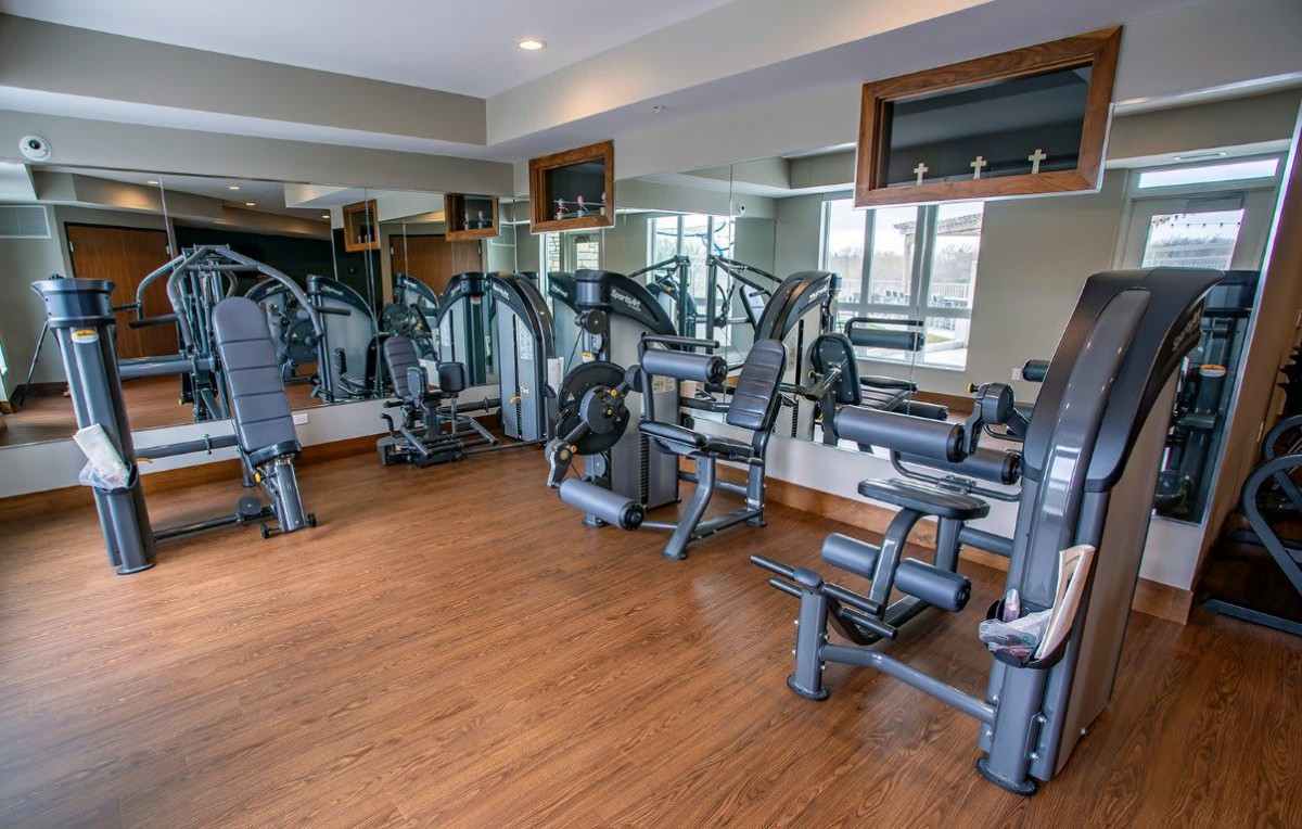 A modern gym with various exercise equipment and mirrored walls.