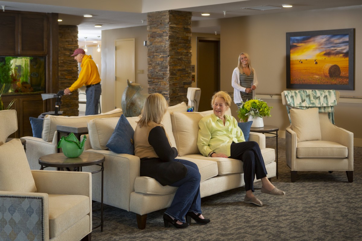 People seated in a lobby area having a conversation with a comfortable and welcoming atmosphere.