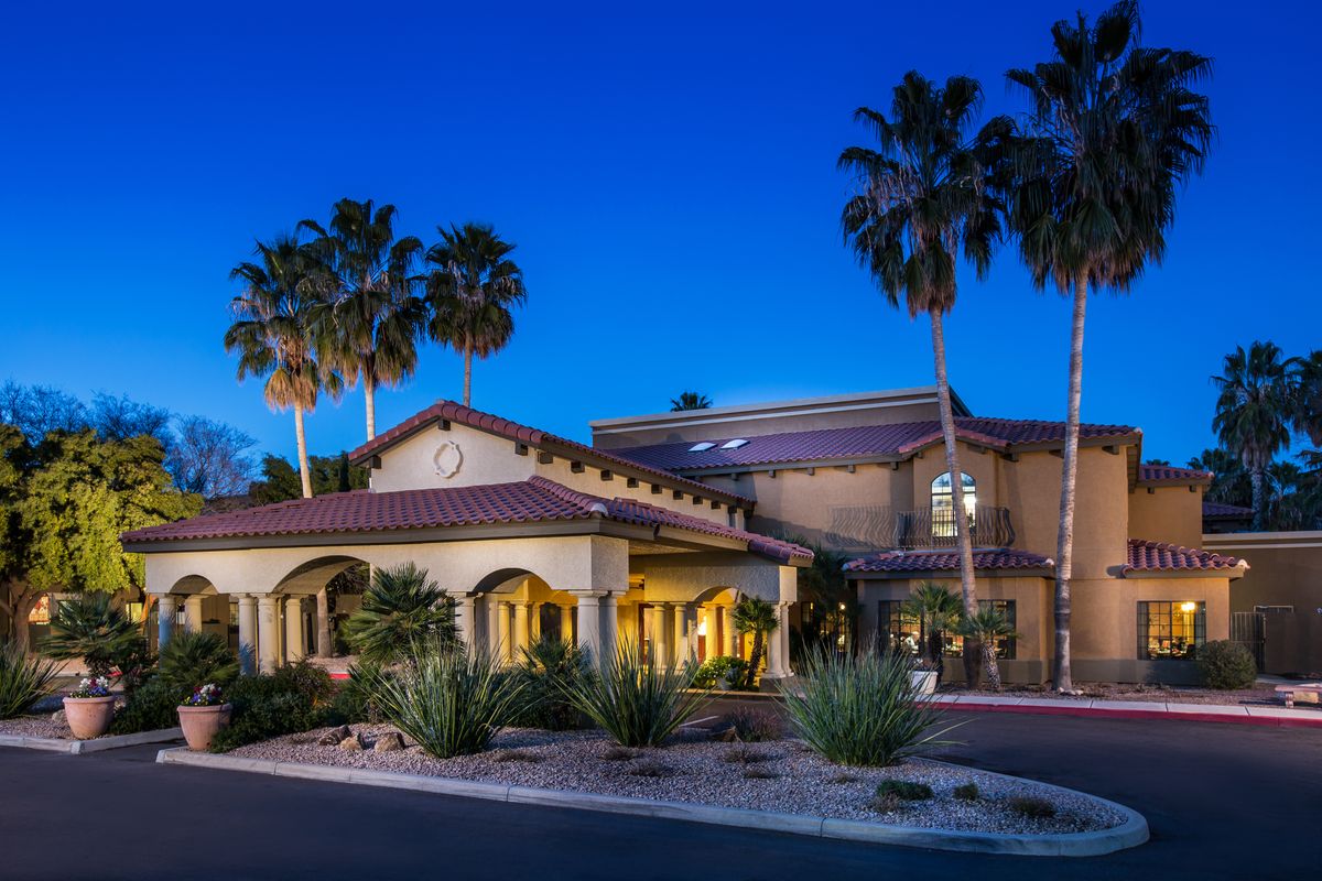 A beautifully lit building surrounded by palm trees at dusk.