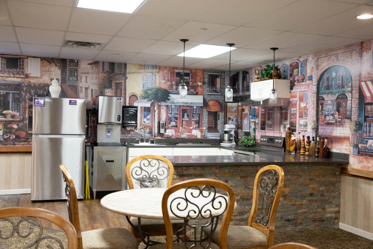 A cozy kitchen and dining area with decorative wall art, a round table with chairs, and modern appliances.