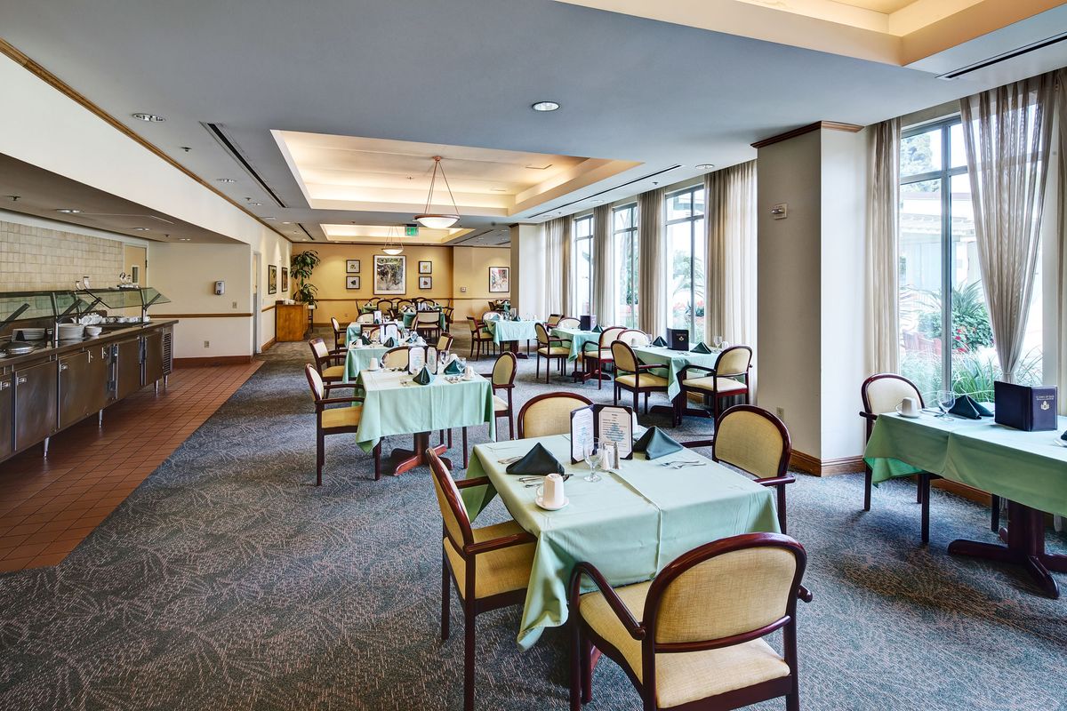 Elegant dining room with tables and chairs set for guests.