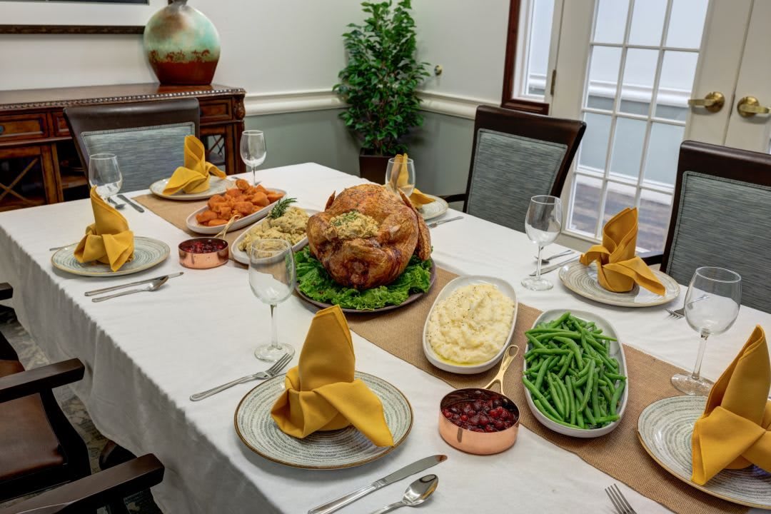 A festive Thanksgiving dinner table set with a roasted turkey and traditional side dishes.