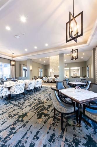A modern and spacious restaurant interior with elegant lighting and well-arranged tables and chairs.