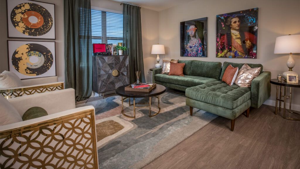 A stylish living room featuring a green velvet sofa, modern coffee table, decorative artwork, and elegant lighting.