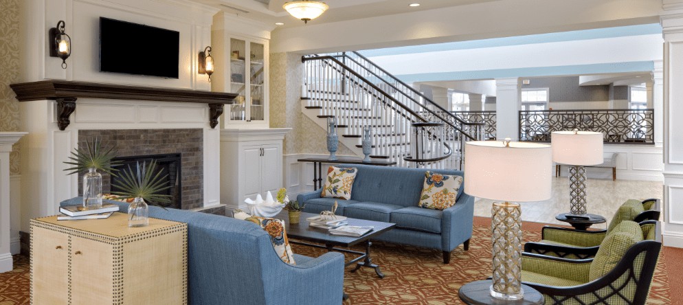A modern living room featuring blue sofas, a carpet, and a sleek staircase.