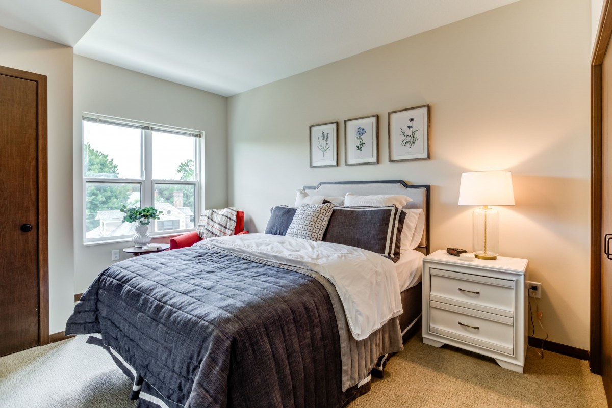 A cozy bedroom with a neatly made bed, soft lighting, and decorative artwork on the wall.