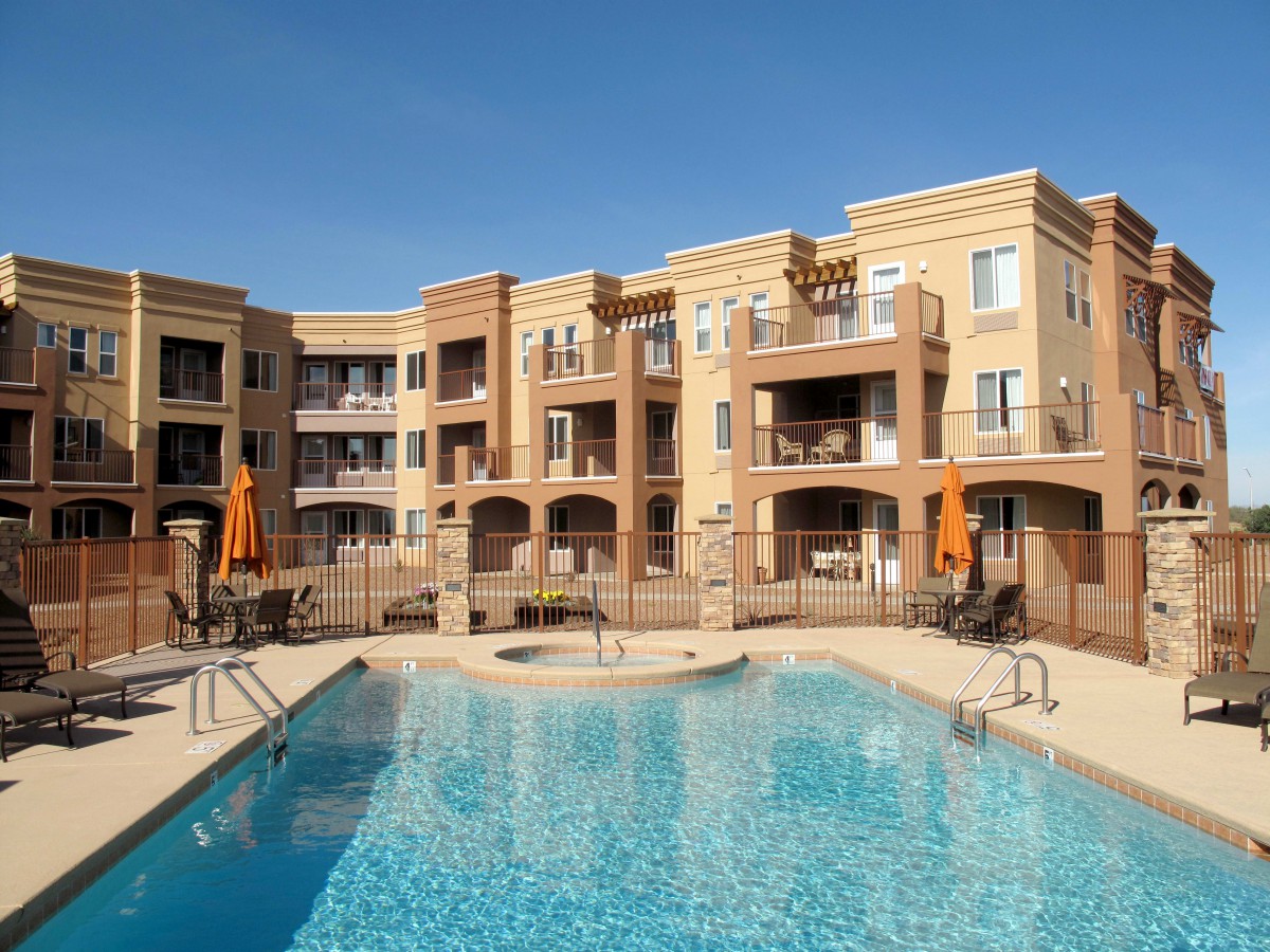 A modern apartment complex with a swimming pool on a sunny day.