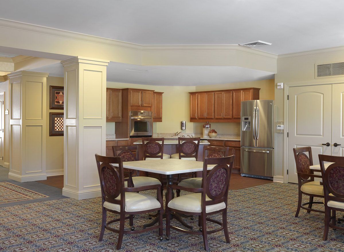 A cozy kitchen and dining area with wooden cabinets, a round table, and chairs.