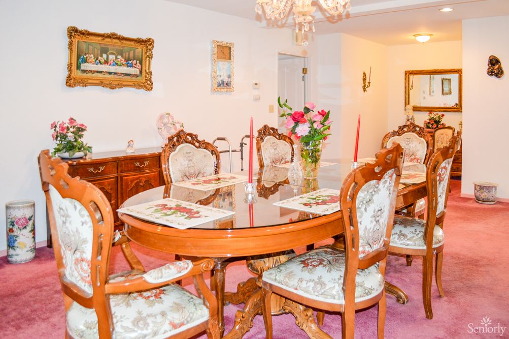 A traditionally styled dining room with antique furniture and a chandelier, featuring a floral arrangement on the table.