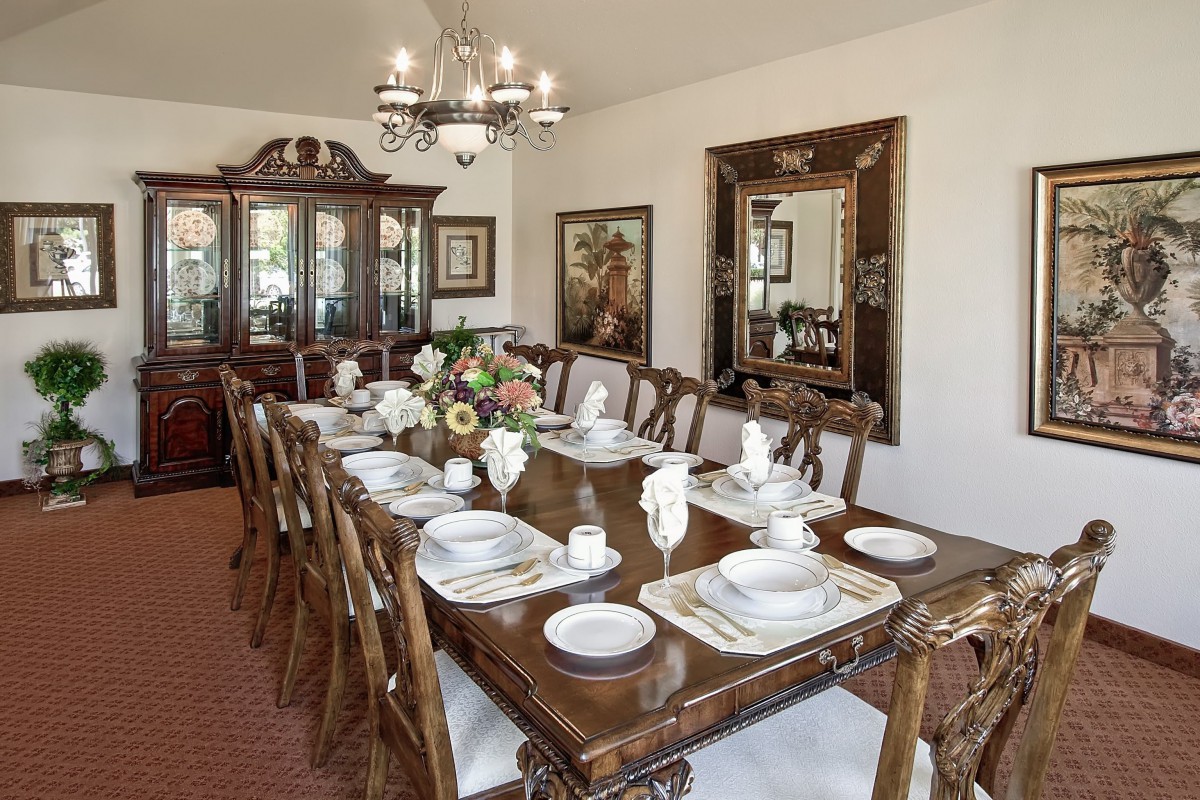 Elegant dining room with a set table, chandelier, and decorative mirror.