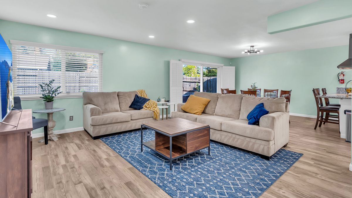 A cozy living room with two beige sofas, a wooden coffee table, and a blue patterned rug.