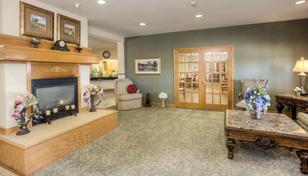 A cozy lobby area featuring a fireplace, seating arrangement, and wooden doors.