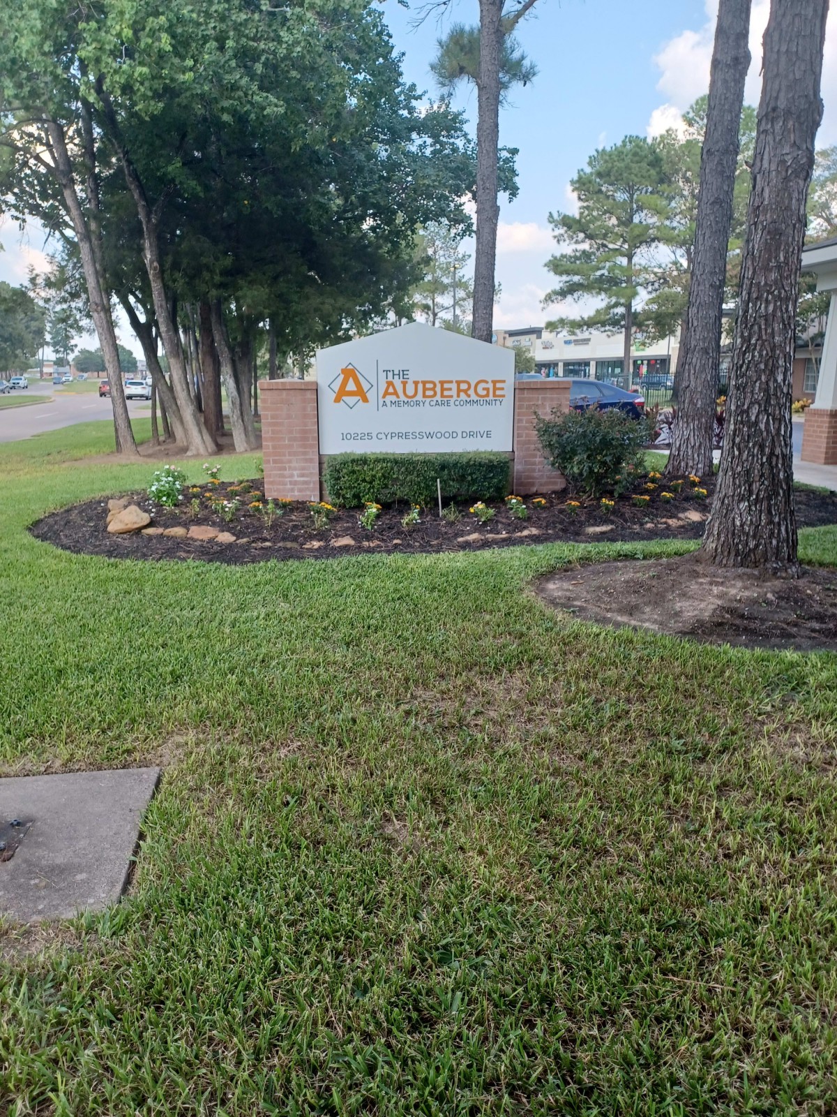 A well-maintained entrance sign surrounded by landscaped greenery and trees.