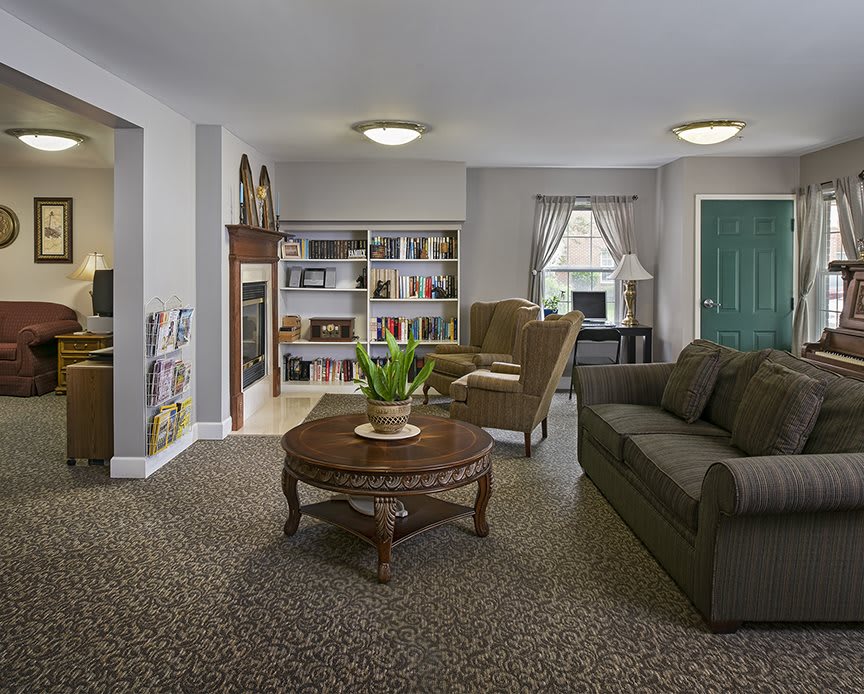 A cozy living room with a sofa, coffee table, bookshelf, and window.