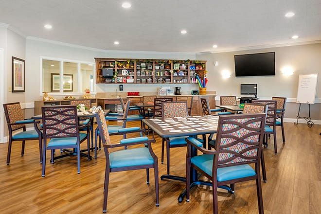 A cozy dining area featuring a bar with various bottles, tables, and chairs arranged neatly.