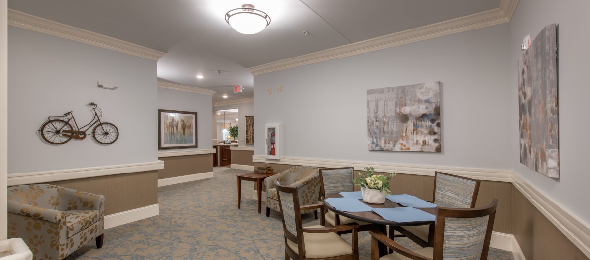 A cozy lobby seating area with artwork, tables, and chairs.