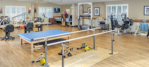 A well-equipped rehabilitation gym featuring various exercise equipment, including a treadmill and parallel bars, designed for physical therapy sessions.