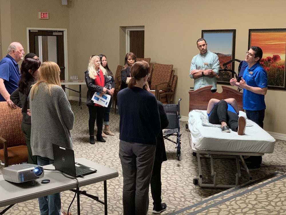 A group of people participating in a medical training session with a demonstration on patient care.