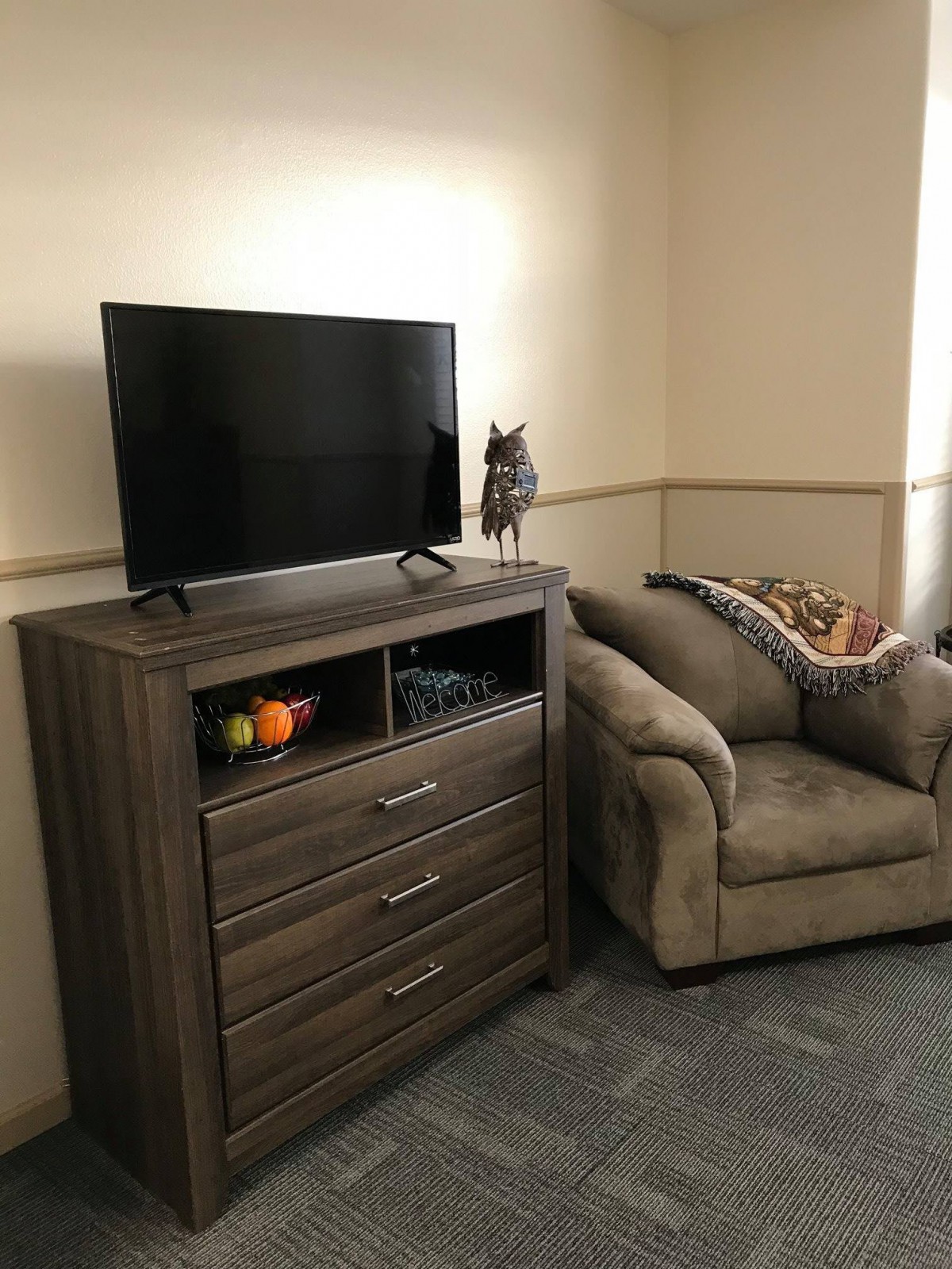A cozy living room corner with a television on a dresser and an armchair nearby.