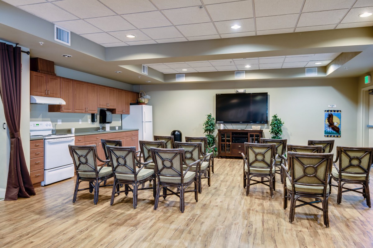 A well-equipped conference room featuring a kitchenette, arranged chairs, and a large television.