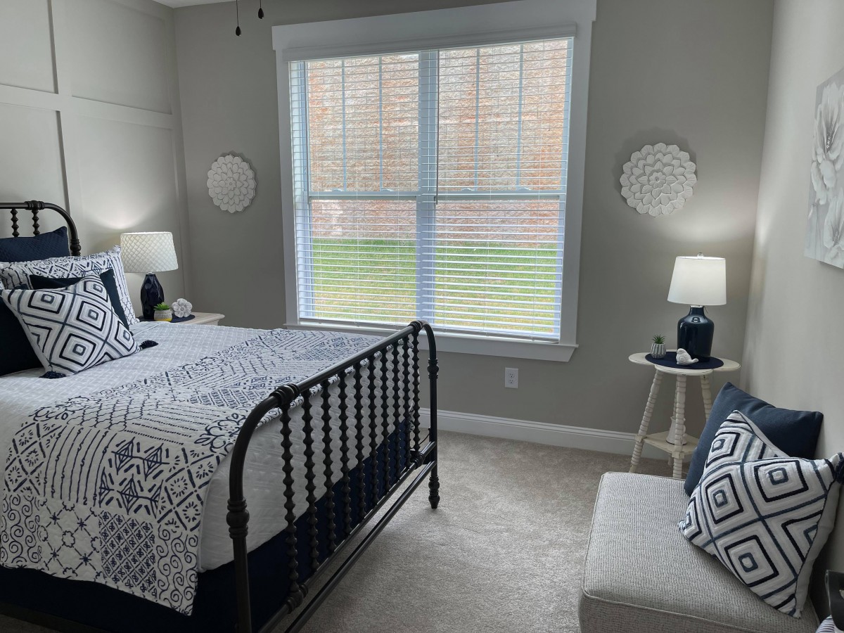 A modern bedroom with a black metal bed frame, geometric patterned bedding, and soft lighting from table lamps on either side of the bed.