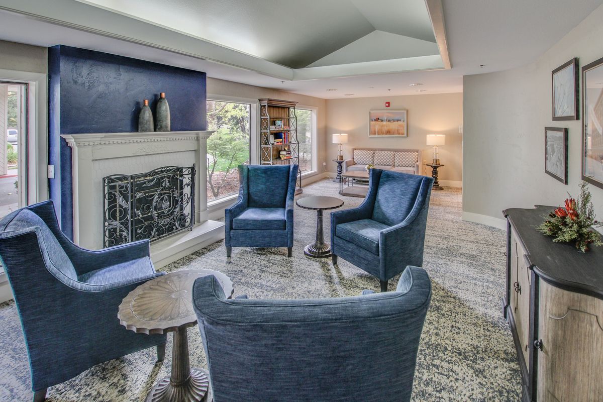 A cozy living room featuring a seating area with blue armchairs, a fireplace, and elegant decor.