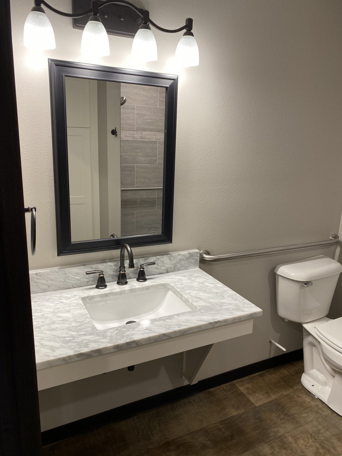 A modern bathroom with a mirror, sink, and toilet.