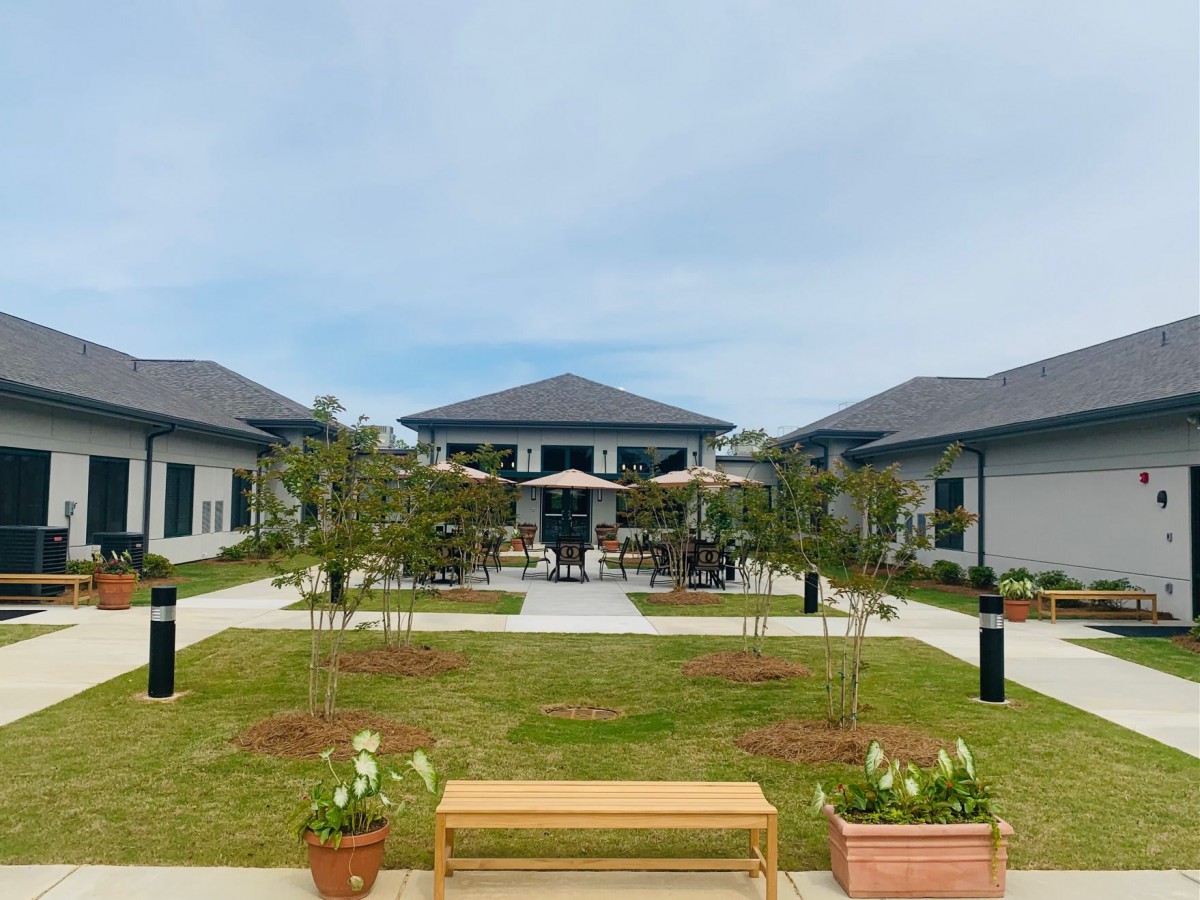 A tranquil courtyard with benches and potted plants, surrounded by modern buildings and outdoor seating.