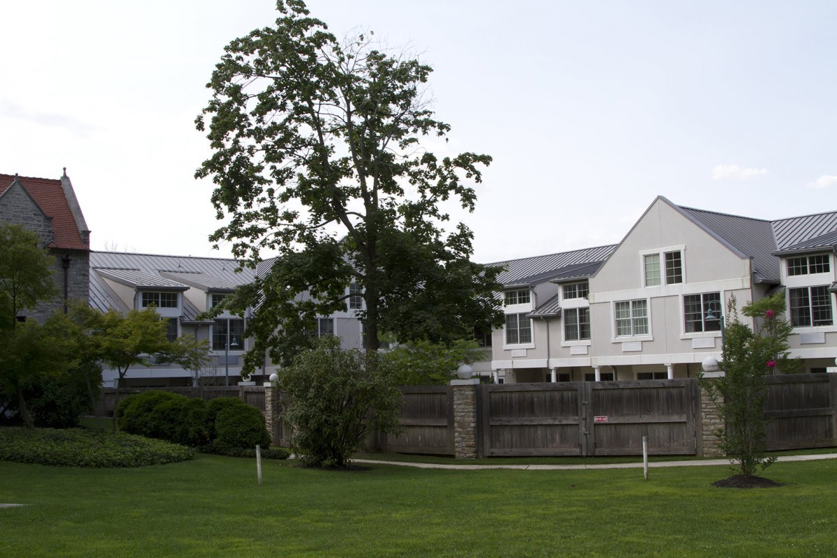 A suburban residential area with white buildings and a tree in the foreground.