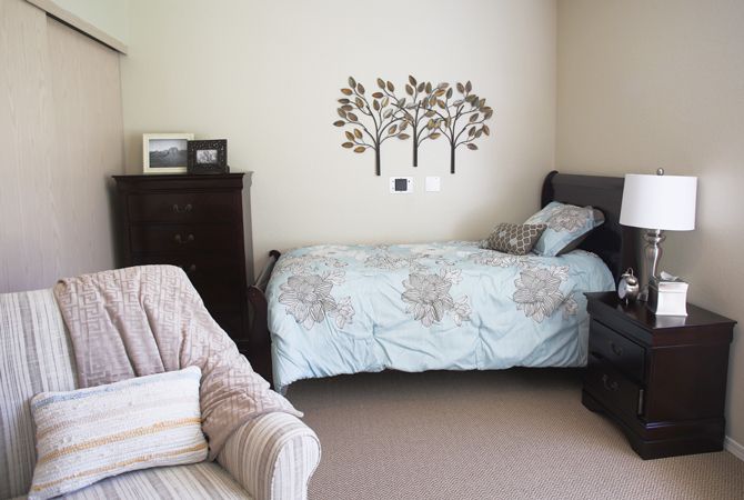 A cozy bedroom with a bed, armchair, and decorative wall art.