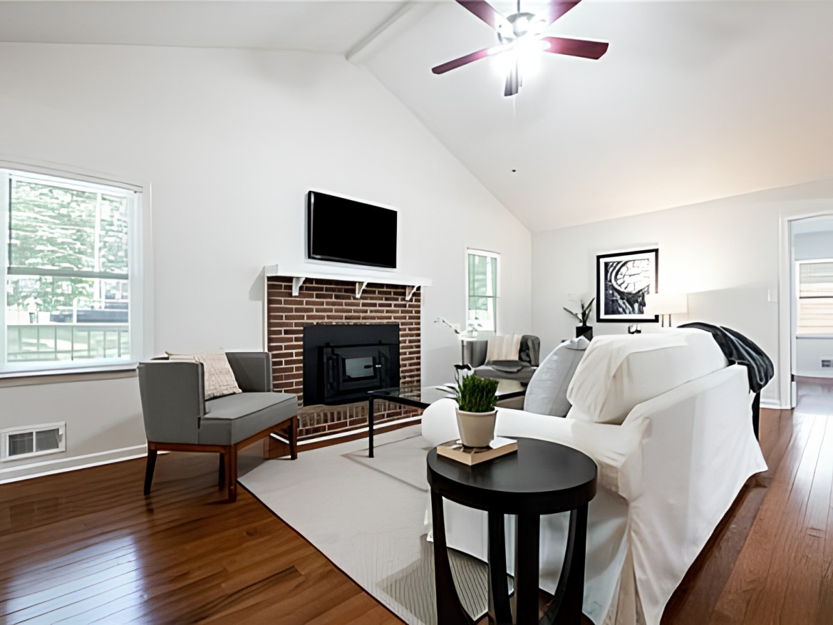 A modern living room with a fireplace, featuring a cozy sofa and armchair on a hardwood floor.