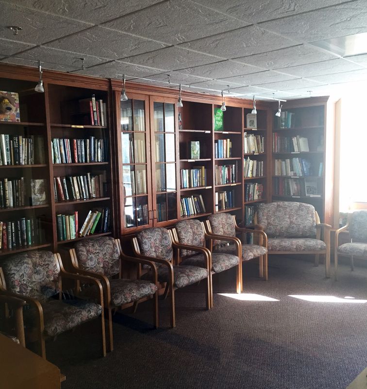 A cozy library corner with shelves full of books and comfortable seating.