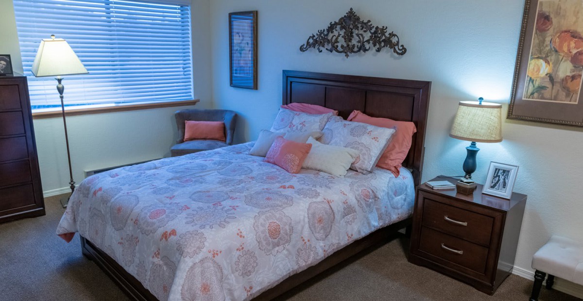 A cozy bedroom with a neatly made bed, decorative pillows, and stylish wall art.