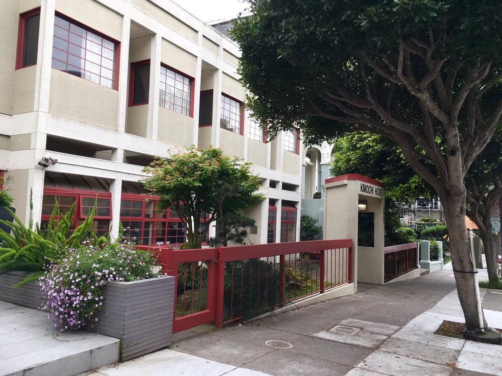 A modern school building with a tree-lined sidewalk.